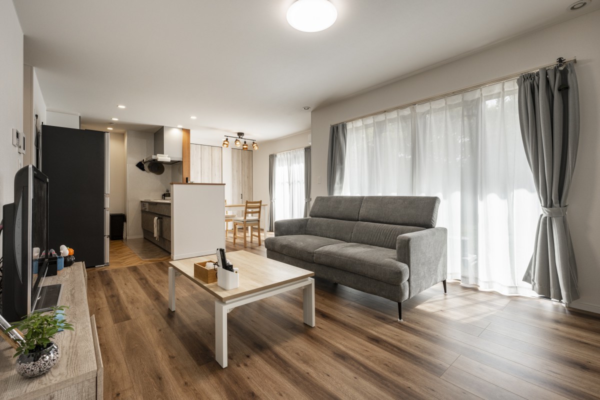 大きい窓からひざしが差し込む居心地の良い明るいリビング