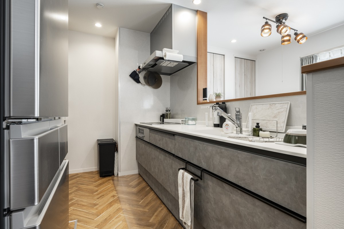 グレージュスタッコ柄のおしゃれなキッチン。作業がはかどる広いワークトップ。床はヘリンボーンのクッションフロア