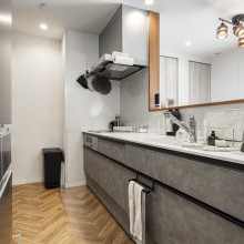 グレージュスタッコ柄のおしゃれなキッチン。作業がはかどる広いワークトップ。床はヘリンボーンのクッションフロア