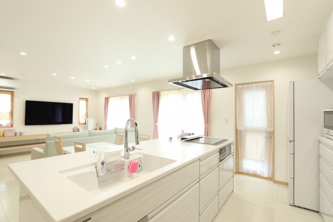 ホワイトカラーの空間に映えるアイランドキッチンのある家